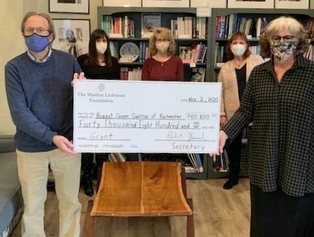 Photo of five people in an office holding an oversized check