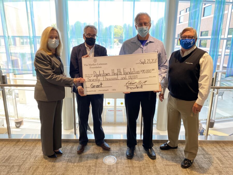 Photo of four people holding an oversized check