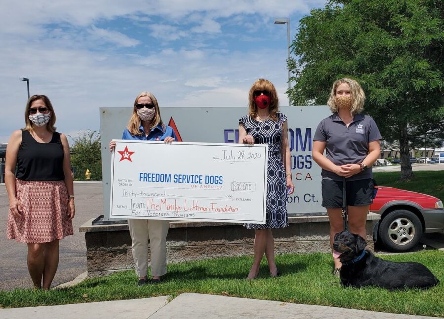 Four people and a dog standing by a large check