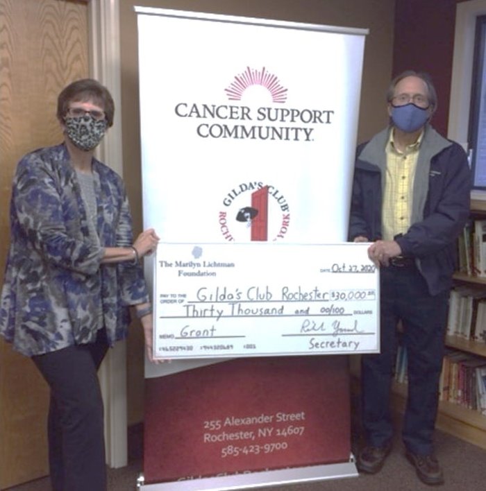 Two people holding an oversized check in front of a banner saying Cancer Support Community