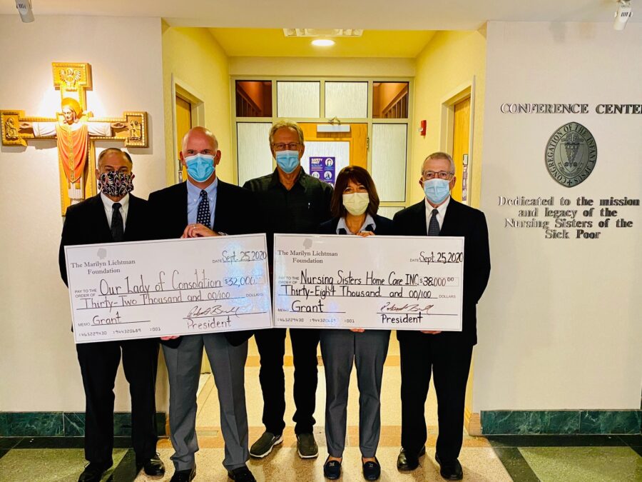 Five people holding up two oversized check