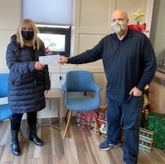 Two people in an office holding a check.
