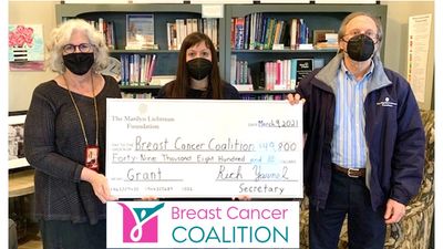 Three people holding oversized check and logo for Breast Cancer Coalition Rochester.