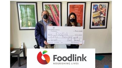 Two people holding oversized check and logo for Foodlink.