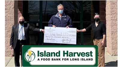 Three people holding oversized check and logo of Island Harvest Food bank.