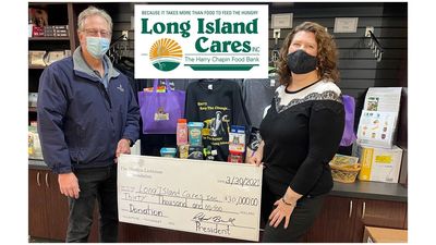 Two people holding oversized check and logo of Long Island Cares. The Harry Chapin Food Bank.